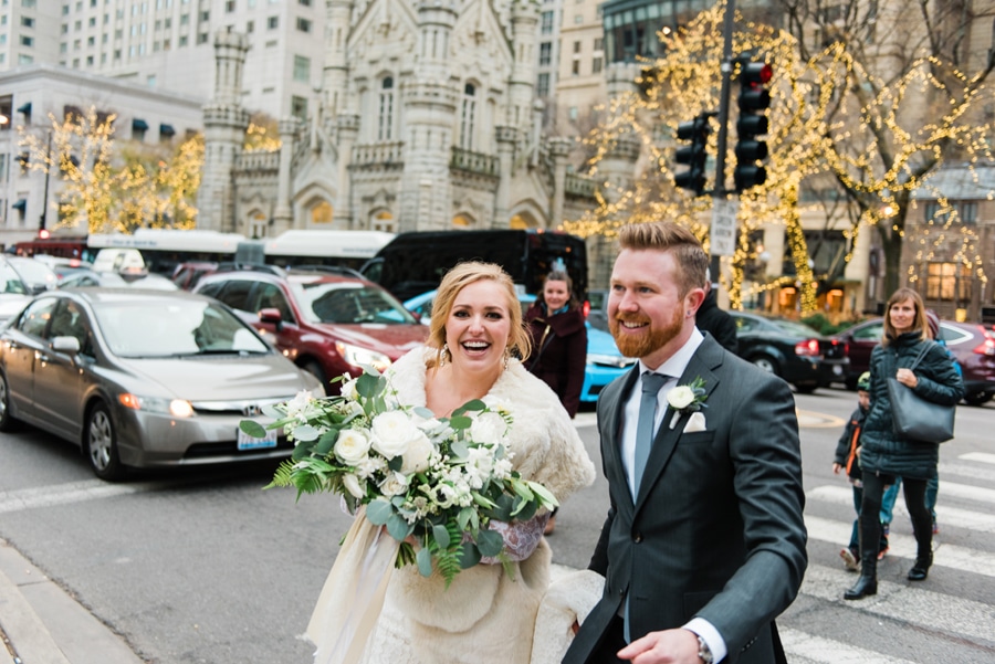 A candid portrait of a bride and groom walking across Chicago's magnificent mile.