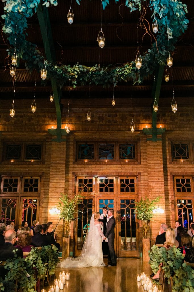 A wedding ceremony at Cafe Brauer with a custom greenery chandelier suspended from the ceiling.