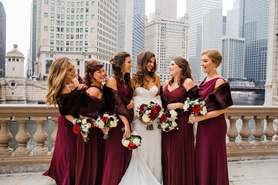 A wedding party poses for a photo in front of the iconic Wrigley Building in Chicago during the winter.