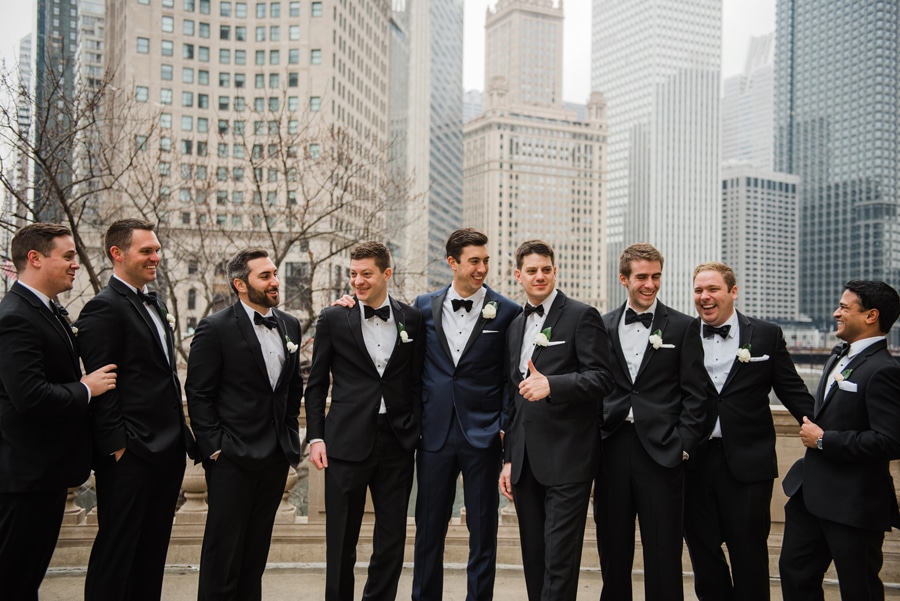 A wedding party poses for a photo in front of the iconic Wrigley Building in Chicago during the winter.