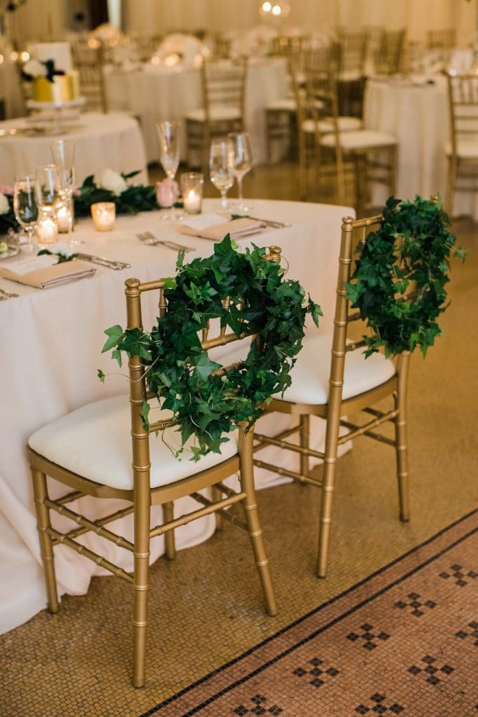 Ivy wreaths placed on the back of the bride and groom's sweet table chairs designed by Life in Bloom.