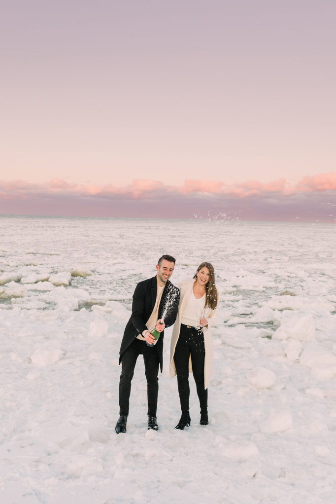 Popping a bottle of champagne at Chicago's lakefront for a winter engagement photo