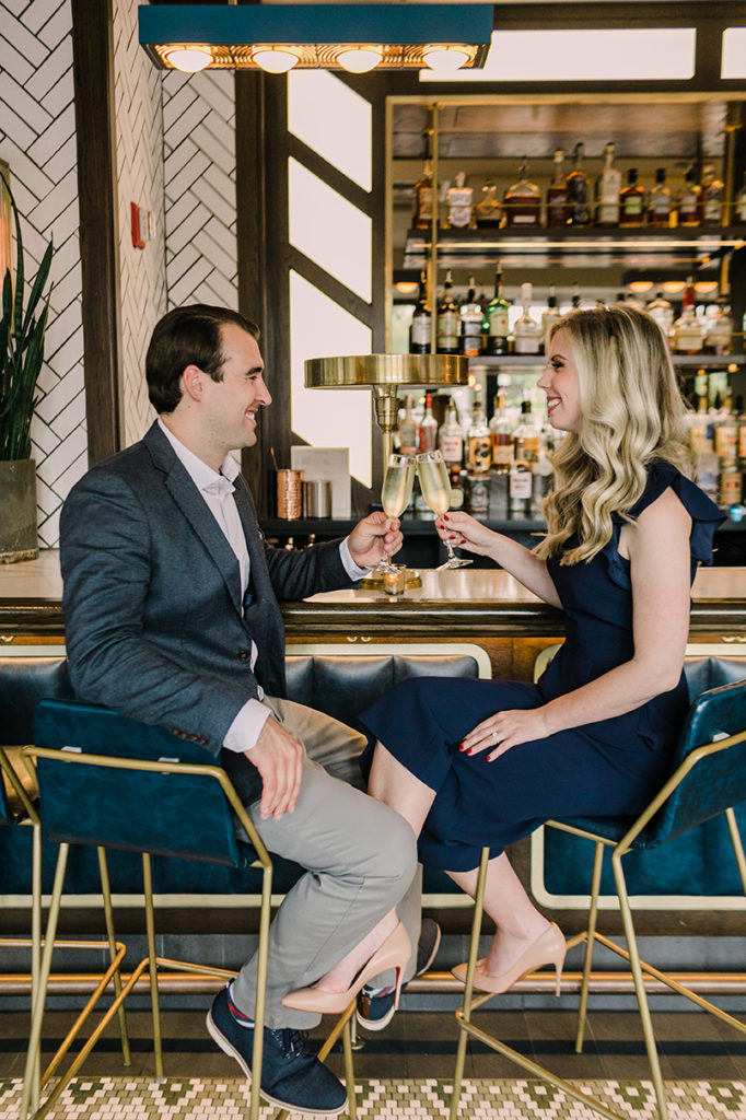 Engaged couple clink glasses to cheers engagement at the Kennison in Lincoln Park