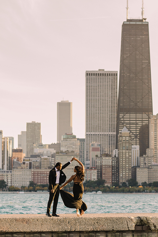 Engaged couple dance in front of Chicago skyline at North Avenue Beach for engagement photo