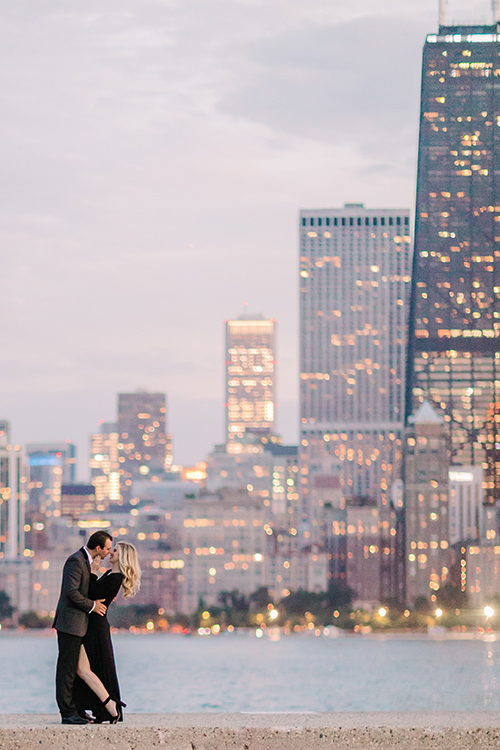 Couple pose in front of glittering city lights for Chicago engagement photo