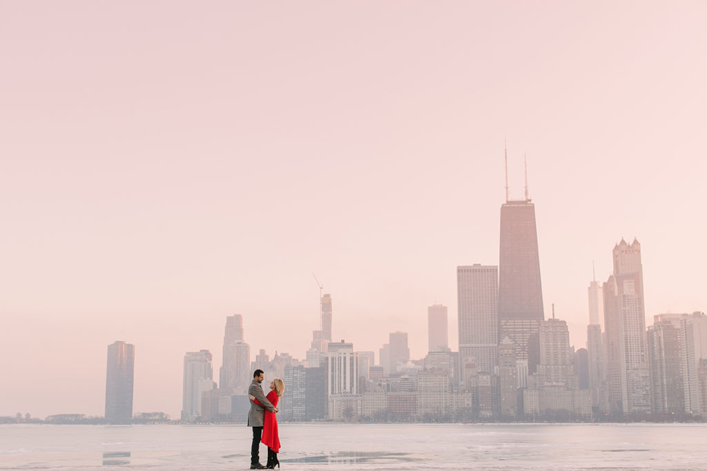 Engaged couple pose in front of the Chicago skyline at sunset