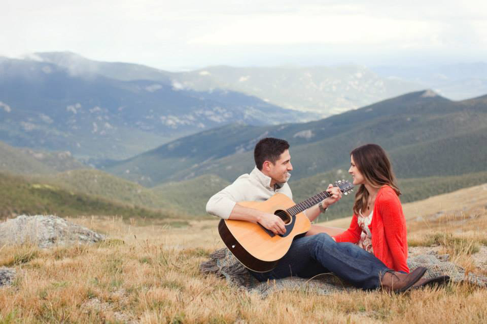 Couple strums guitar during engagement session in Colorado mountains.