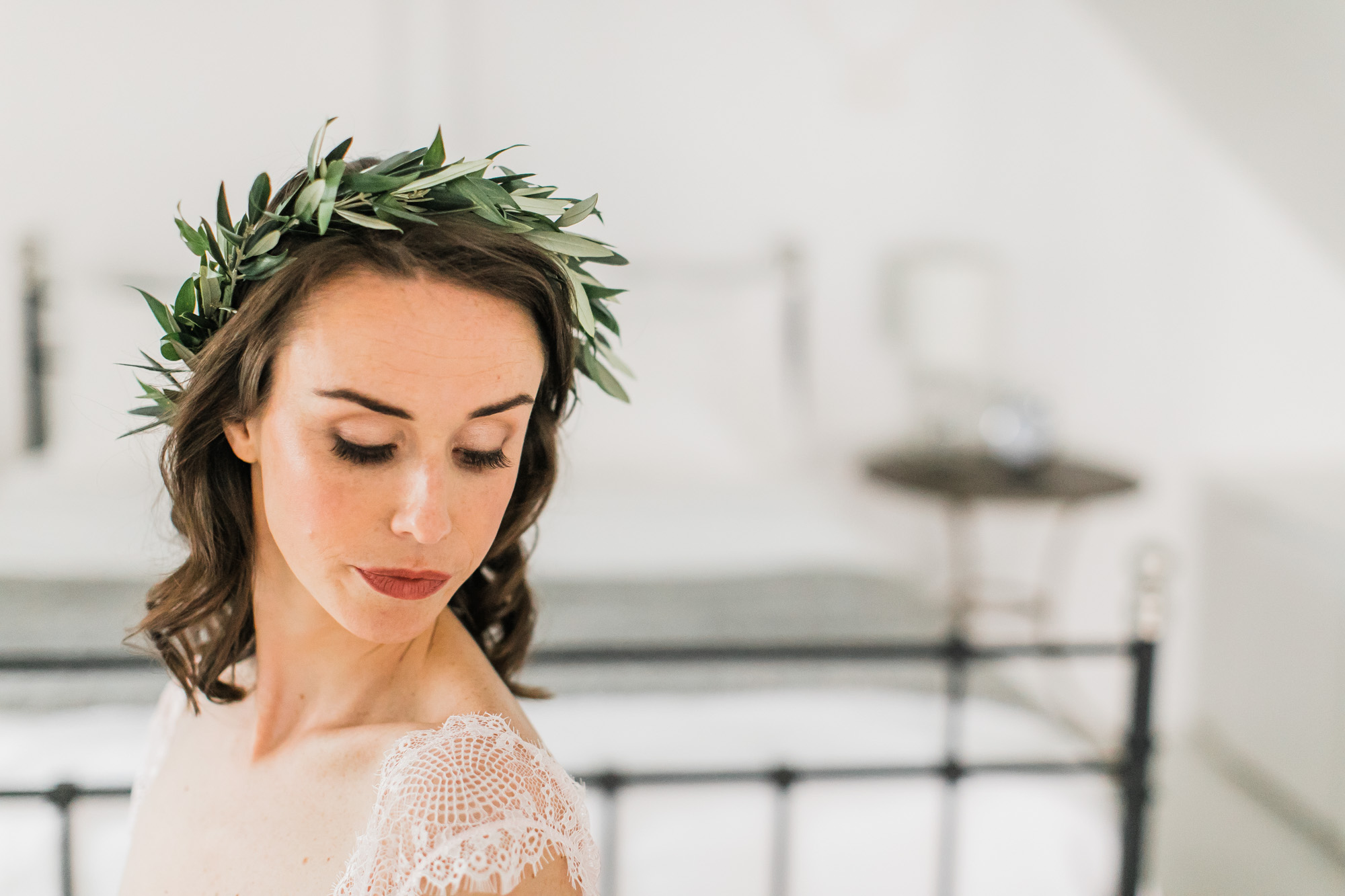 A bride wears an olive wreath floral crown for her boudoir photo