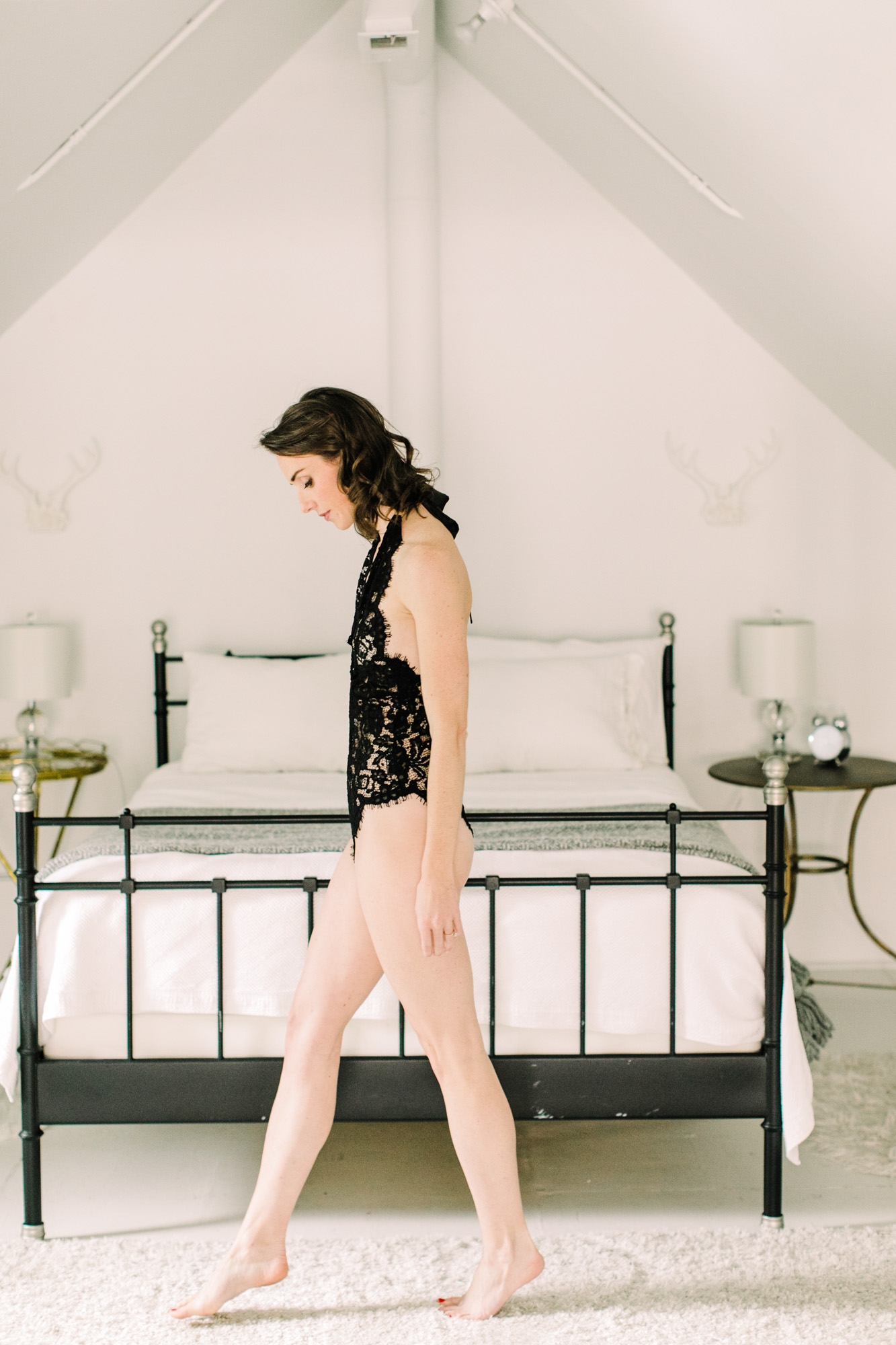 A woman walks across the bedroom for her boudoir shoot.
