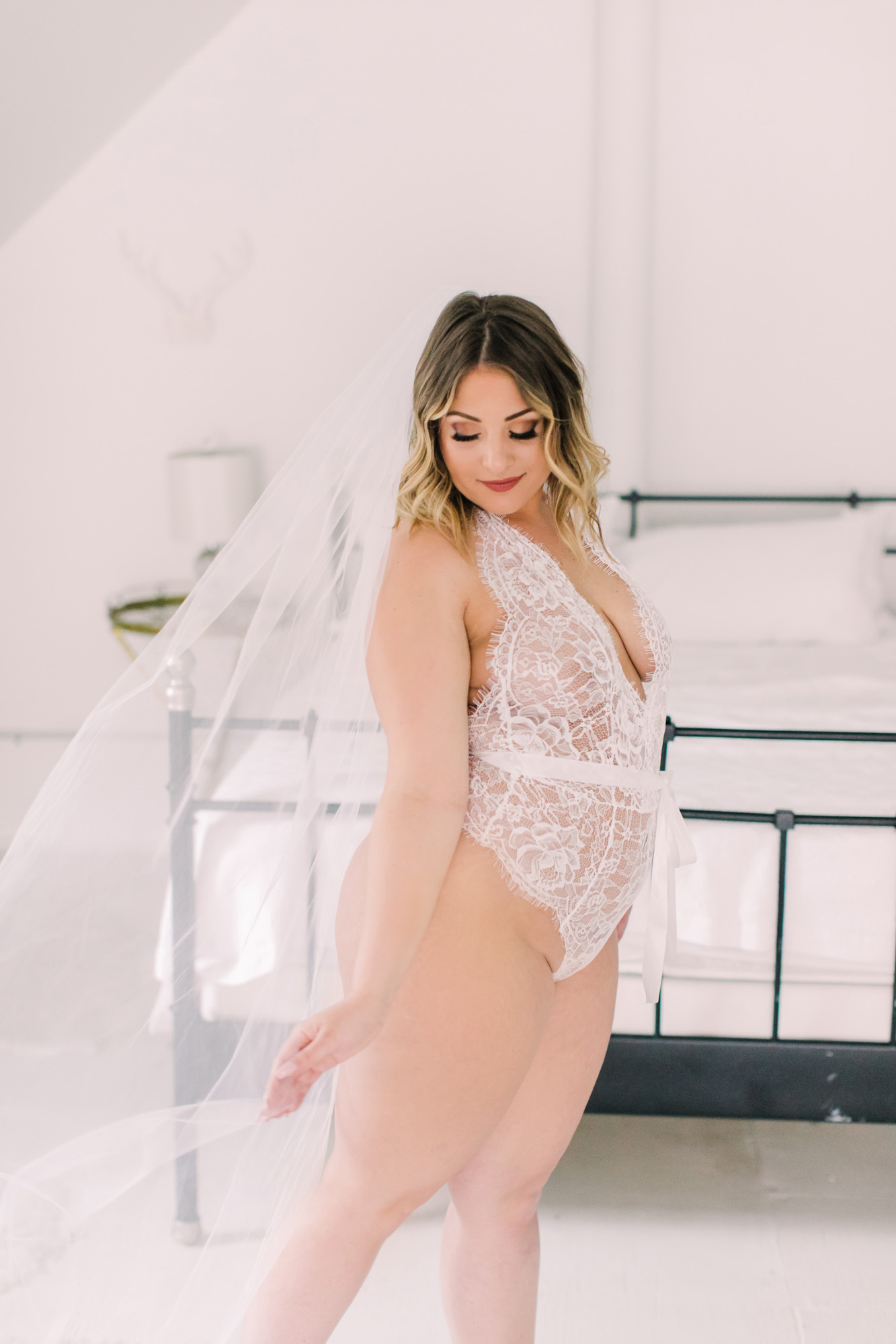 A bride wears white lingerie and a wedding veil for her bridal boudoir photo session in Chicago.