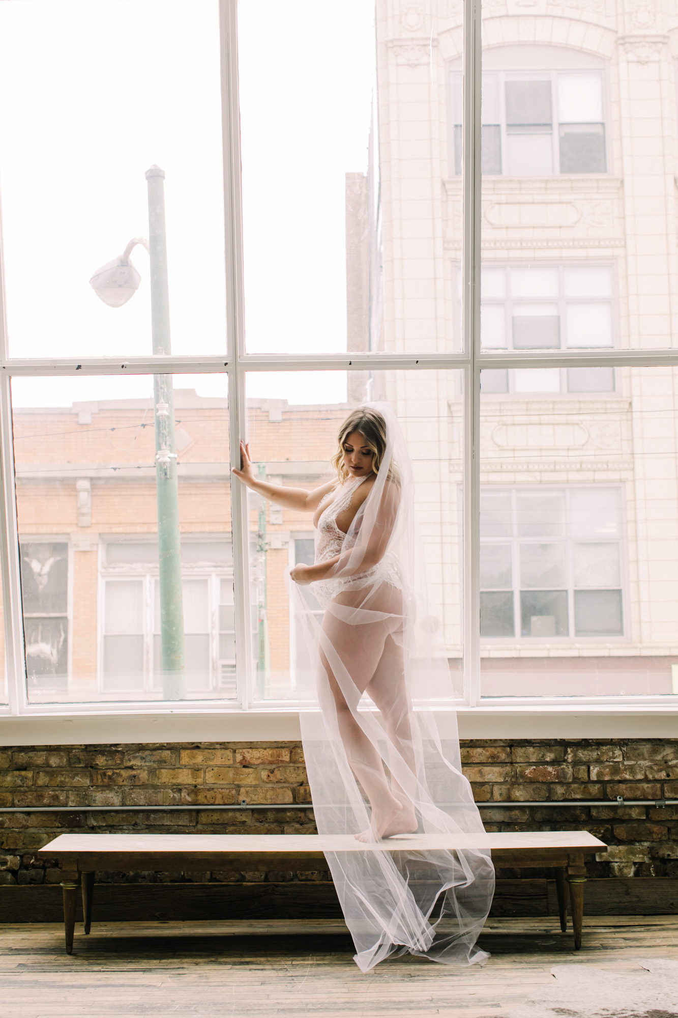 A bride poses in white lingerie and a wedding veil for her bridal boudoir shoot in Chicago.