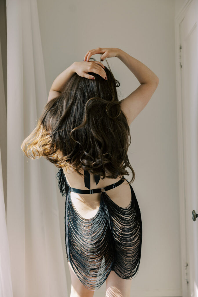 Back view of woman wearing black strappy lingerie in natural light