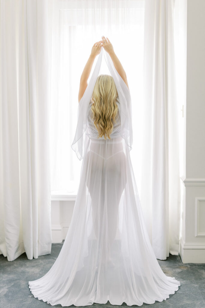Woman standing in long flowing robe backlit by window