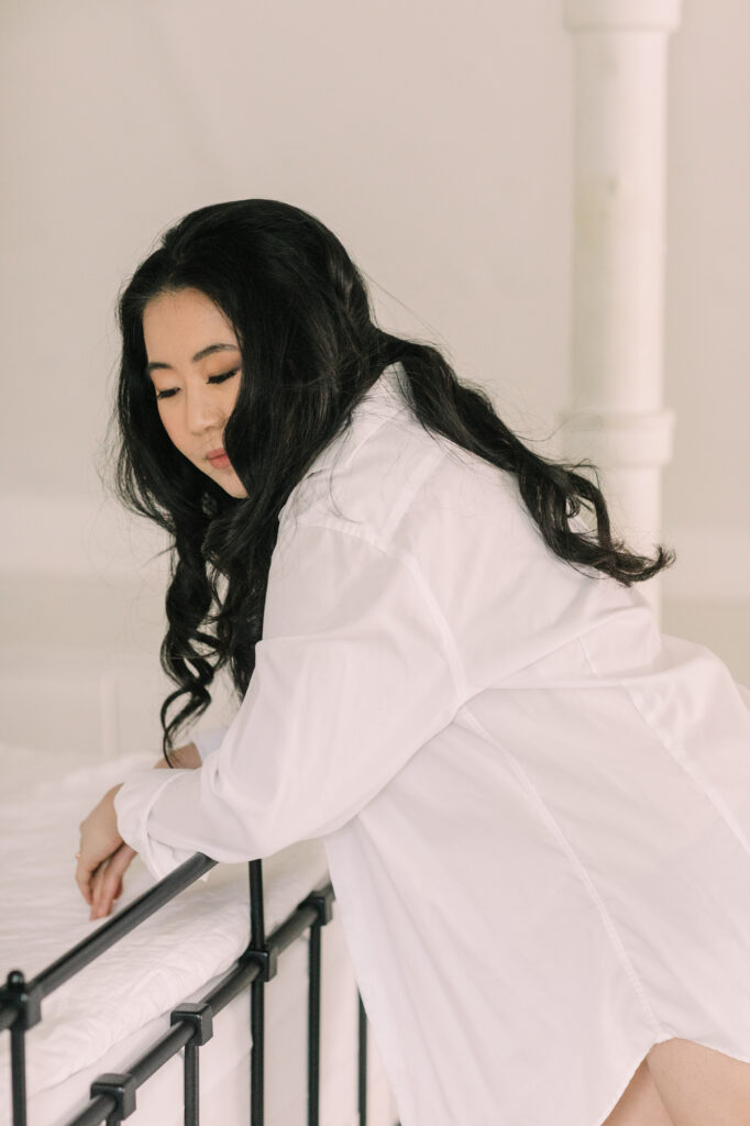 Woman wearing oversized white button down shirt on staircase boudoir session