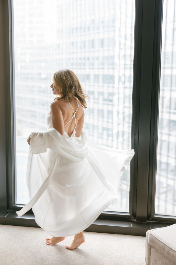 Woman walking in sheer robe in window light boudoir session