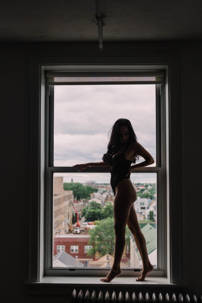 A moody boudoir pose standing in the window
