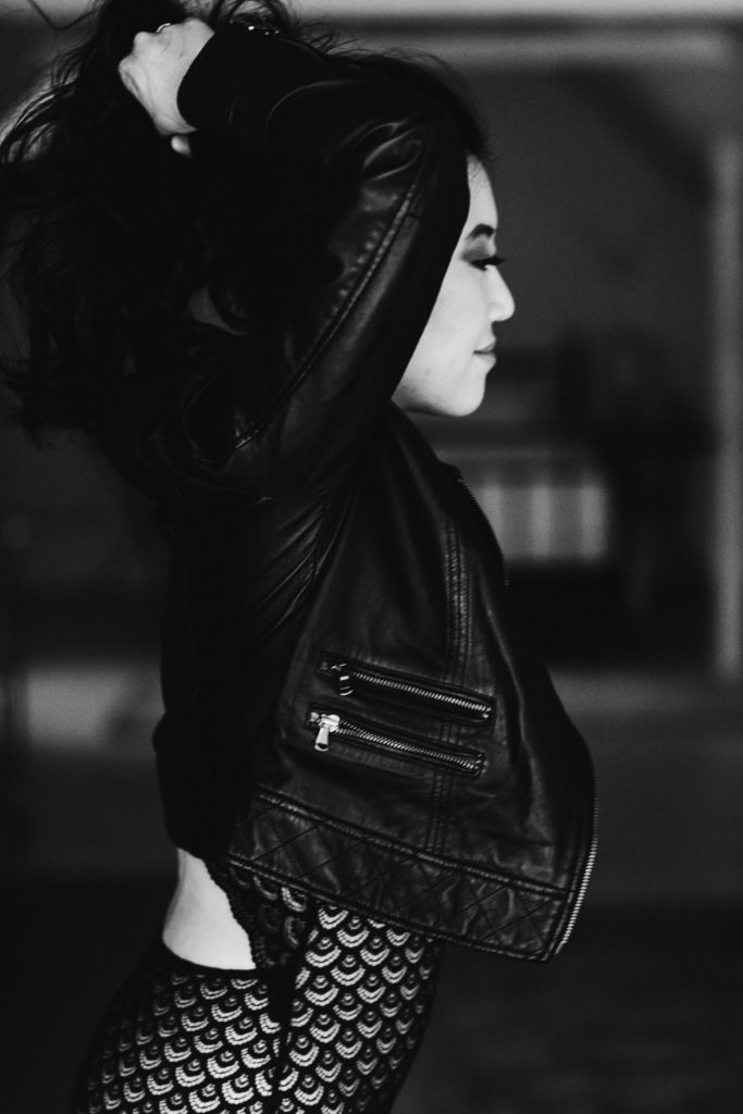 An edgy and chic boudoir photo with a leather jacket and black bodysuit.