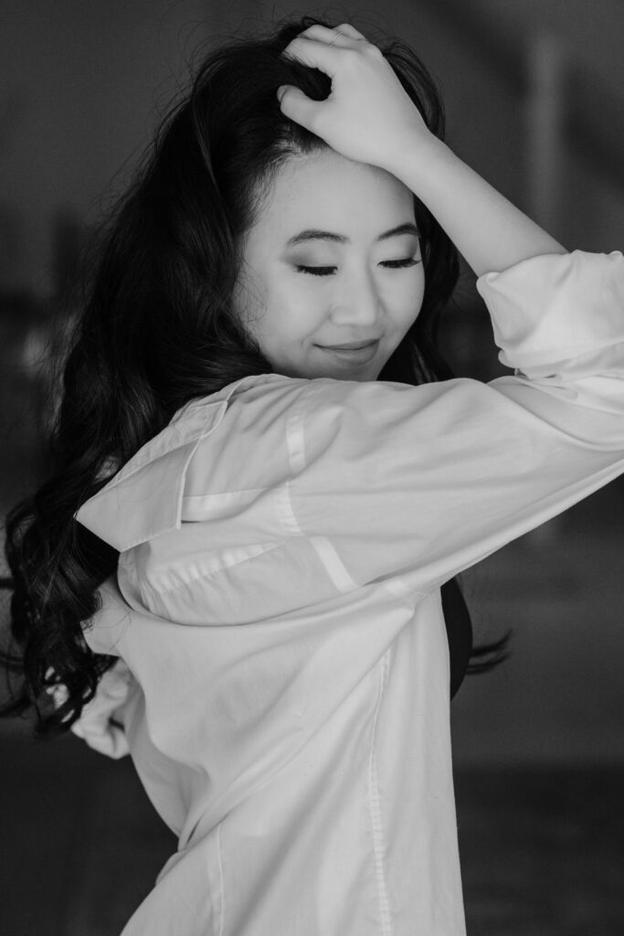 Boudoir photo of a woman wearing an oversized button-down shirt in soft natural light