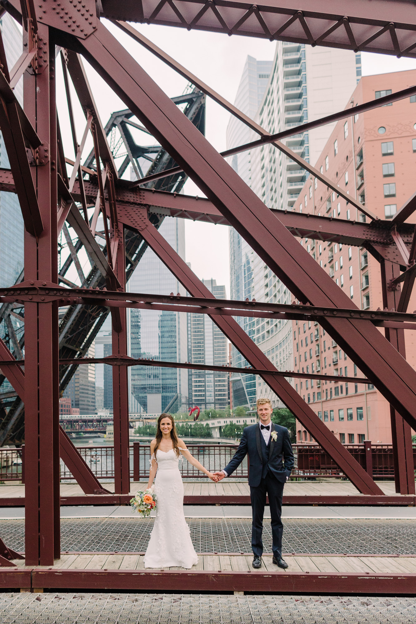 Bride and groom pose on the Kinzie Street Bridge in Chicago's West Loop for a portrait.