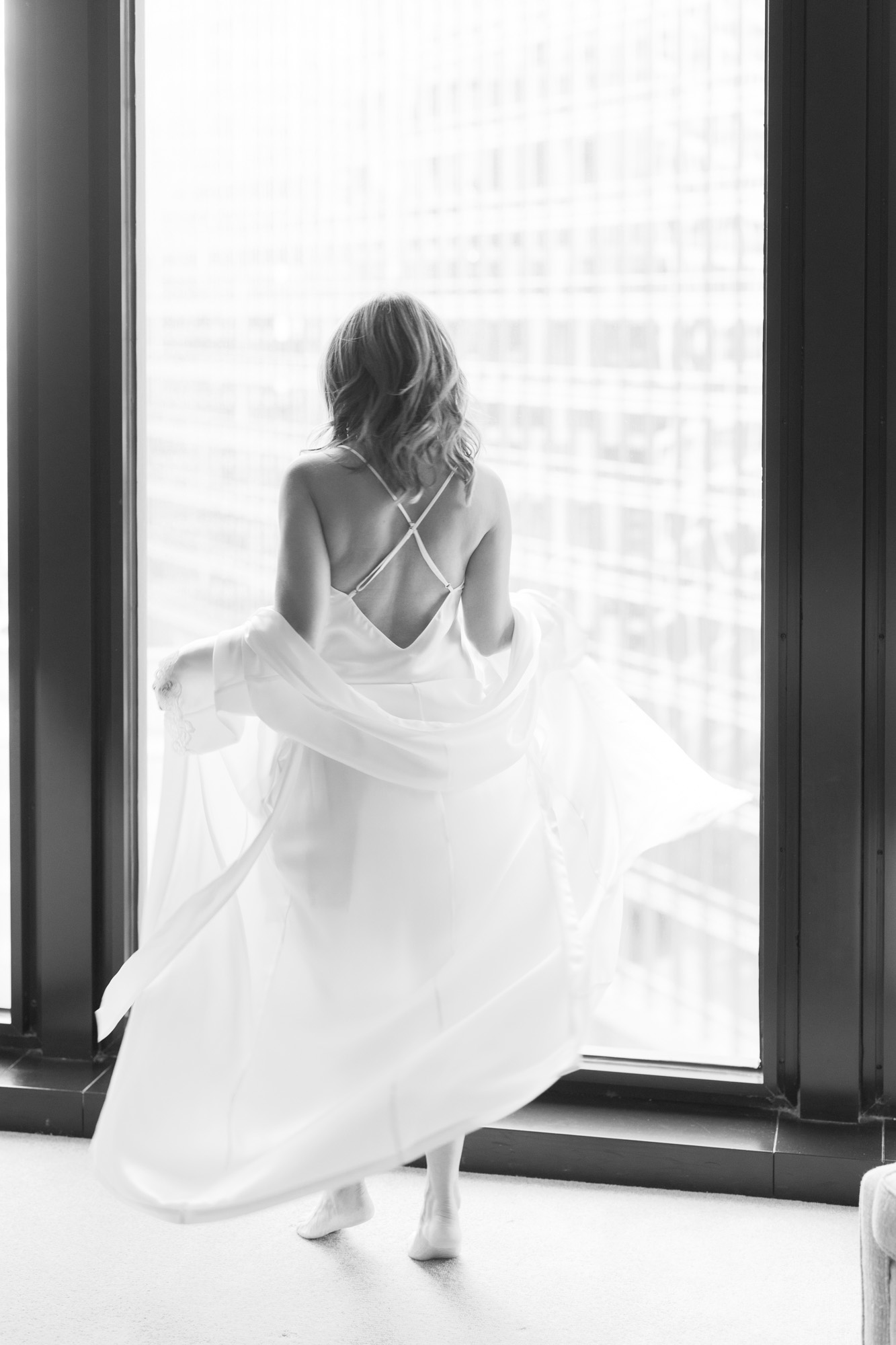 A woman twirls around in her luxurious robe for a boudoir photo.