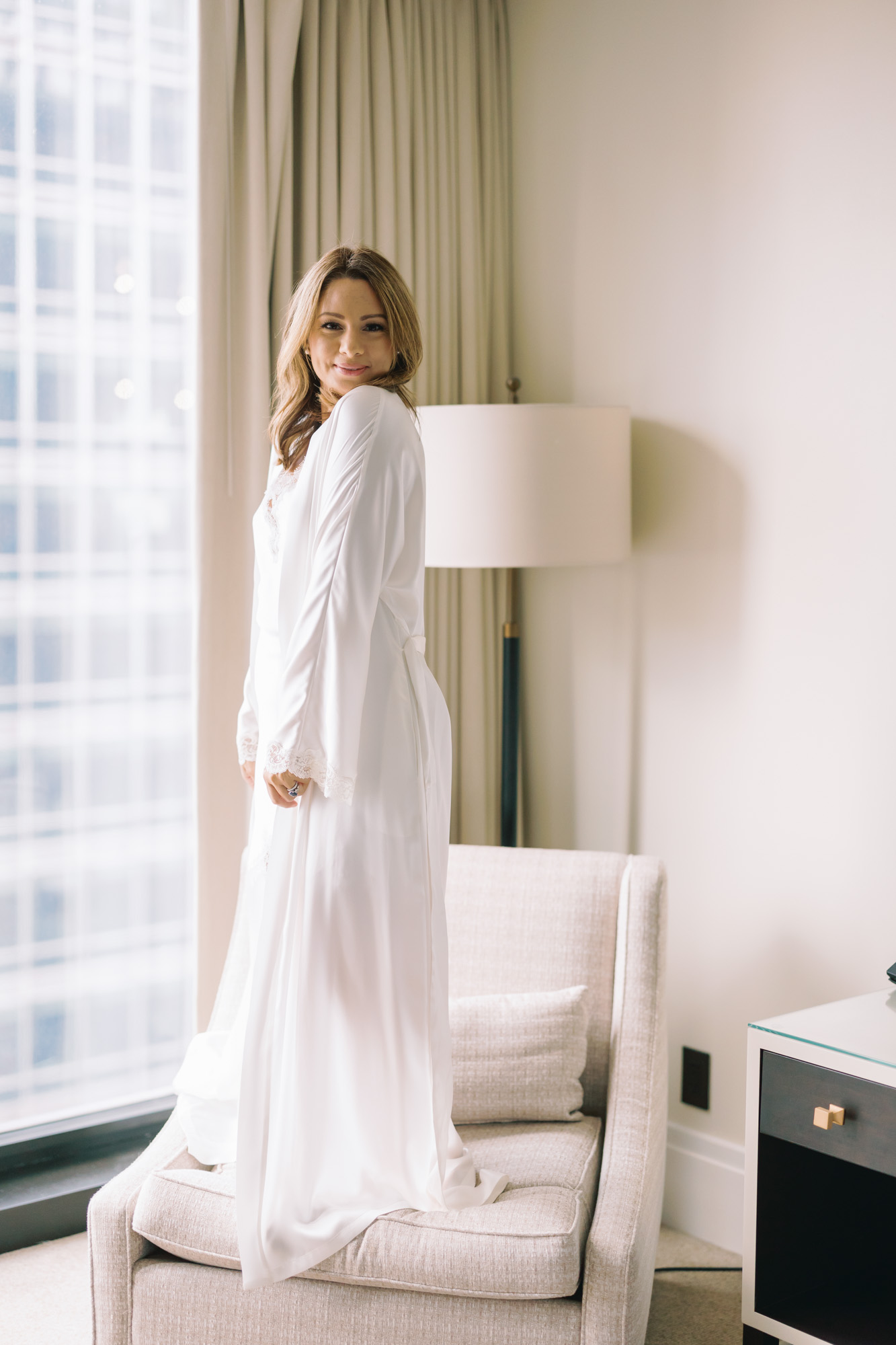 A woman poses for a boudoir photo while wearing a long, elegant robe.