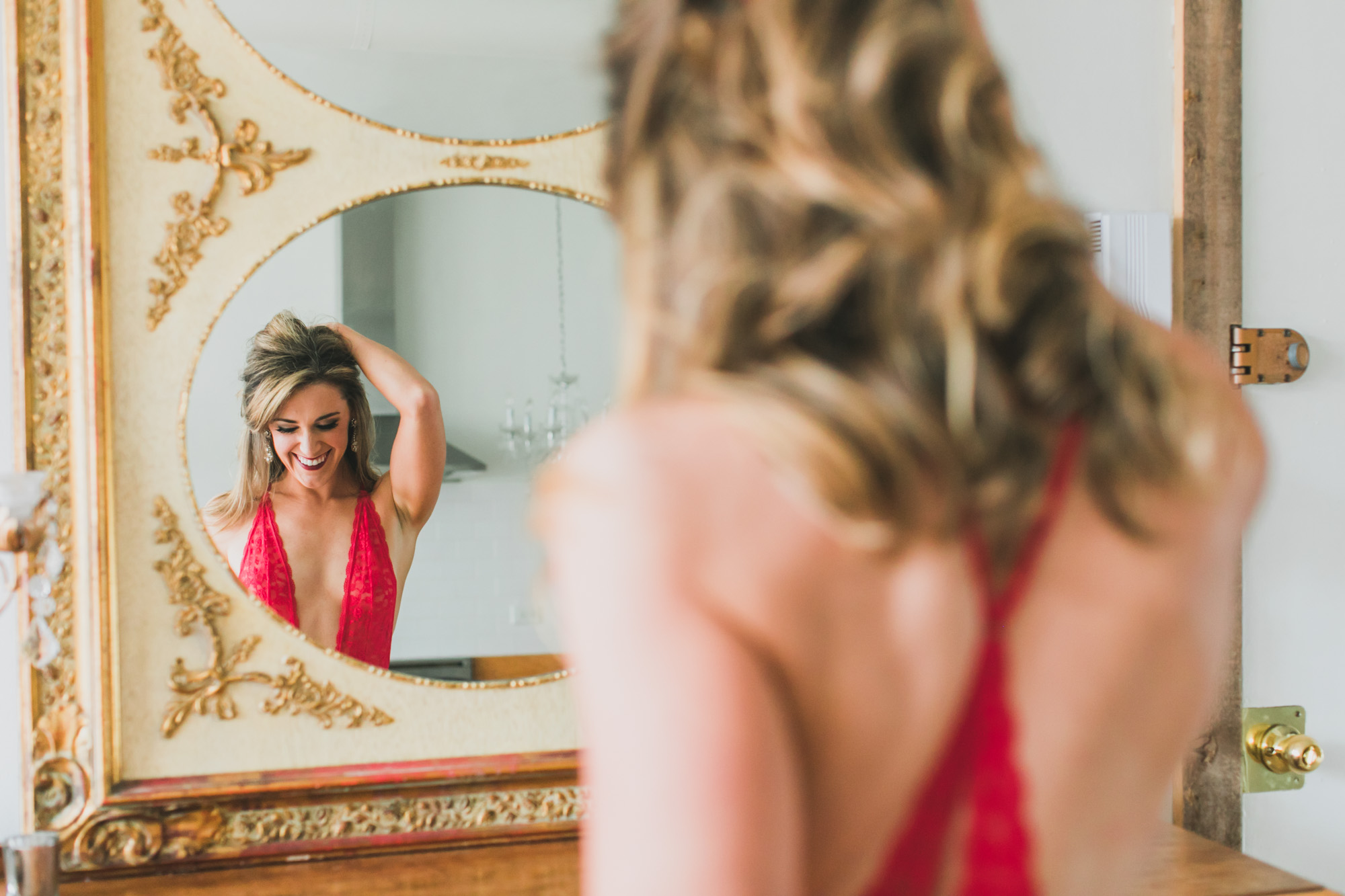 A beautiful mirror reflection boudoir photo of a woman wearing red lingerie.