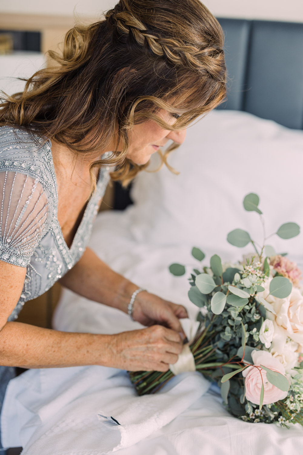 A bride's mother fastens a broach on a bridal bouquet.