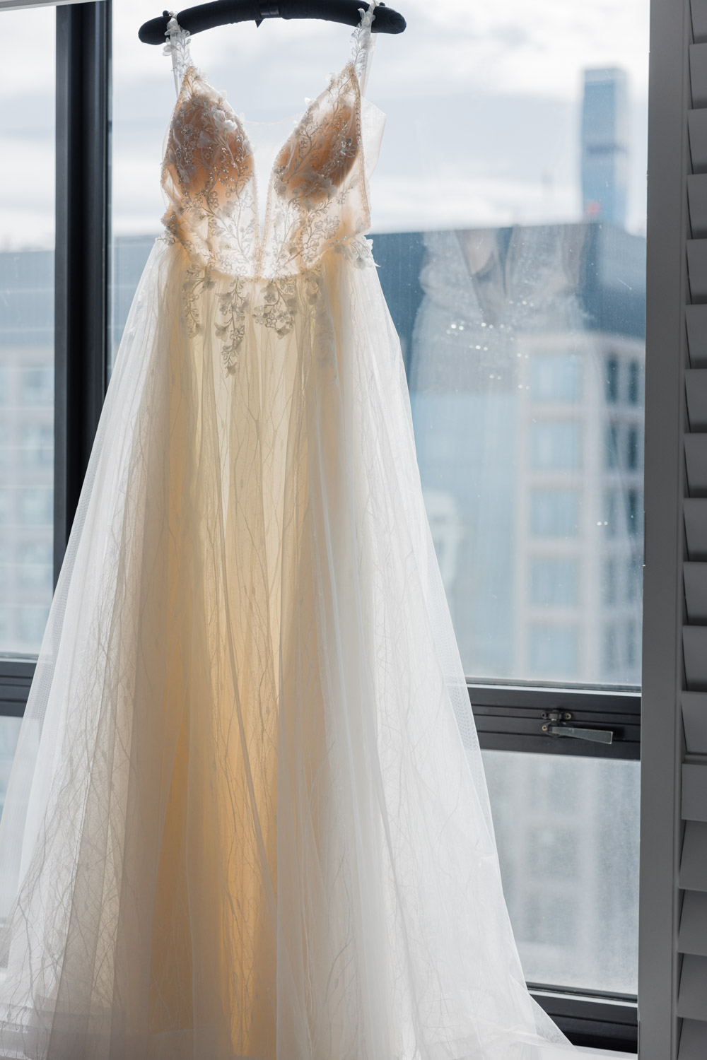 A wedding dress hanging in the window of the Ritz Carlton hotel in downtown Chicago.