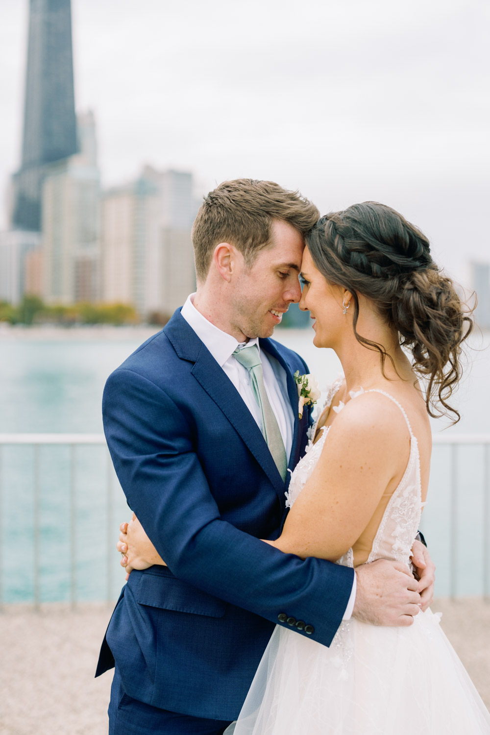 A bride and groom pose in front of the Chicago skyline at Olive Park.