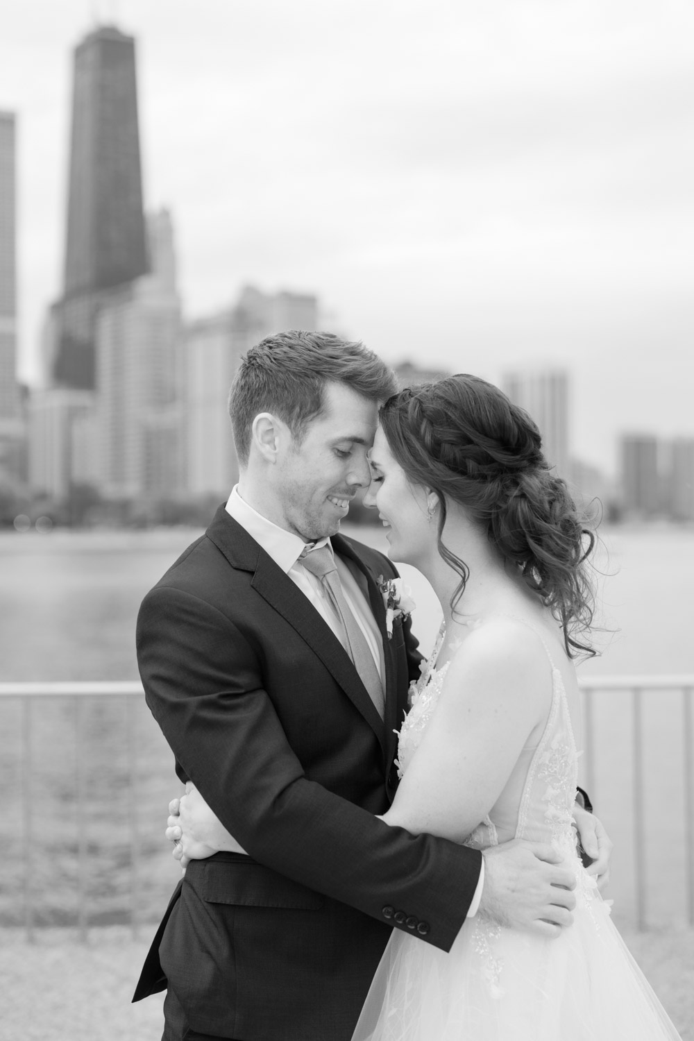 A bride and groom pose in front of the Chicago skyline at Olive Park.