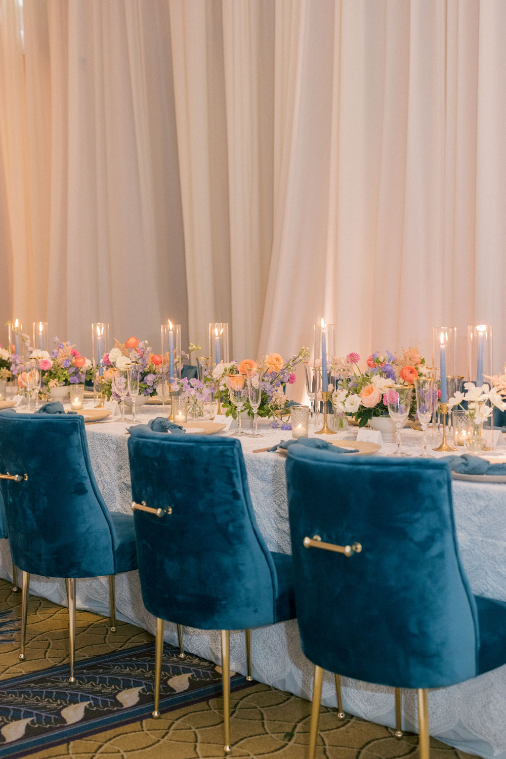 A wedding reception with blue velvet chairs and colorful flowers.