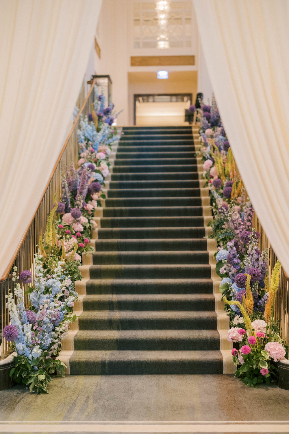 The Peninsula Chicago staircase lined with colorful floral arrangements.