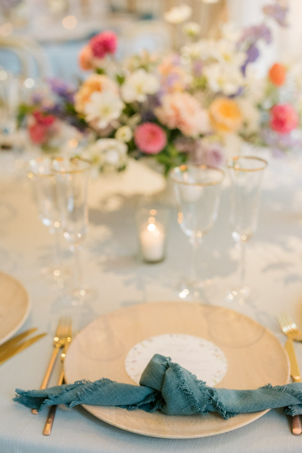 A bamboo charger and teal linen napkin for a colorful wedding reception.