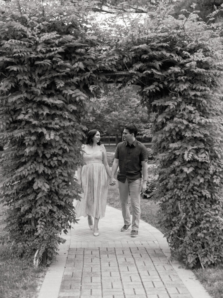 Elmhurst engagement photographer, Artistrie Co., captures a black and white engagement photo of a couple walking and holding hands.