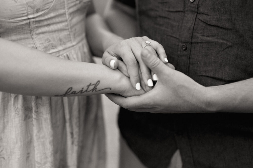 A detail photo featuring a bride's engagement ring and a tattoo spelling "faith"
