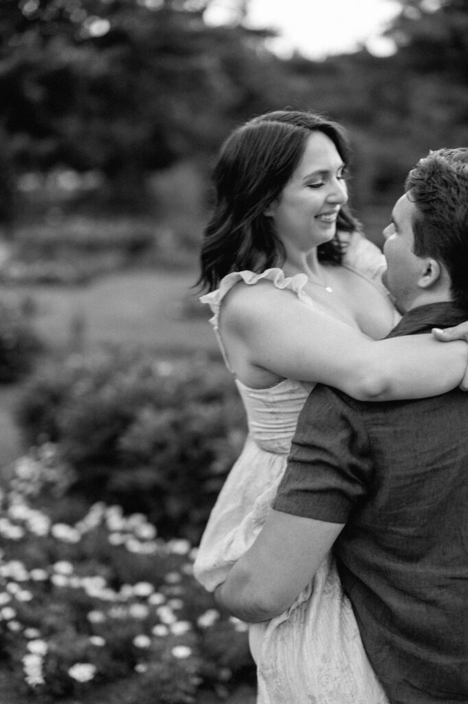 A blurry black and white engagement photo captured at sunset in a secret garden in Elmhurst
