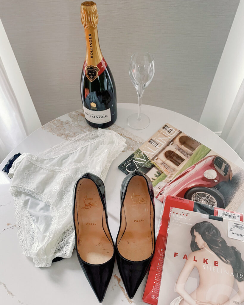 Luxury boudoir details with Christian Louboutin heels, champagne, and delicate lingerie at The Talbott Hotel