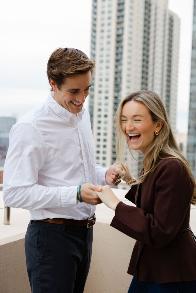 Couple laughing together moments after the proposal with Chicago skyline behind them.