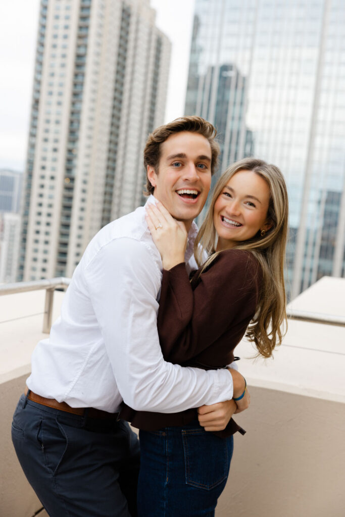 Couple laughing together moments after the proposal with Chicago skyline behind them.