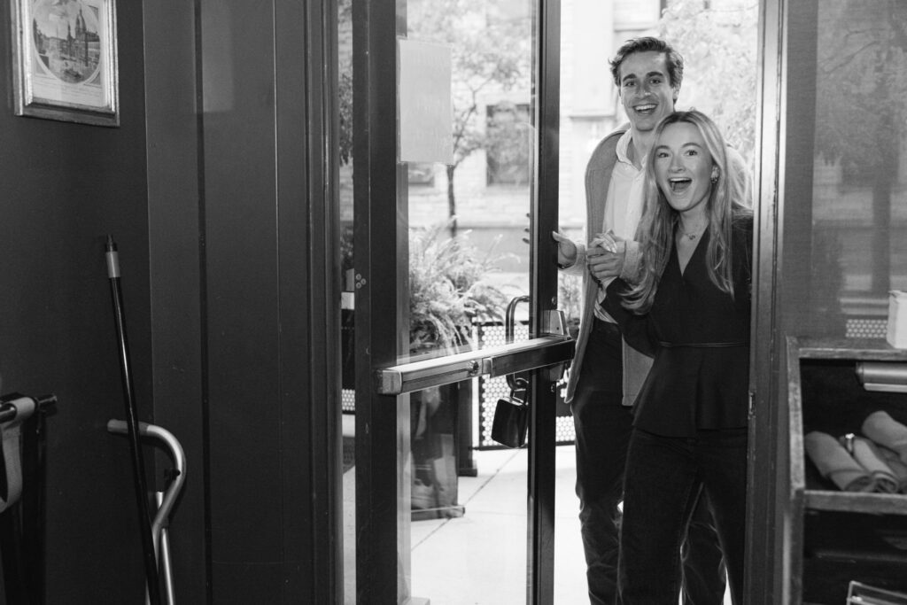 Couple walking into a bar in Chicago to a surprise engagement party with friends and family.