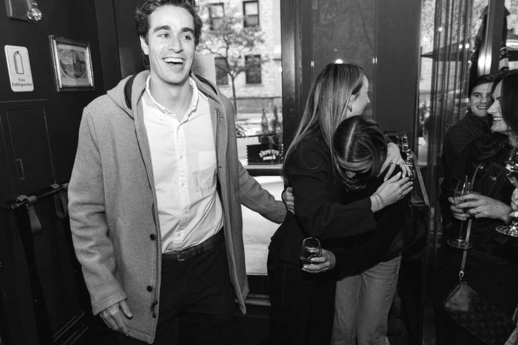 Couple walking into a bar in Chicago to a surprise engagement party with friends and family.