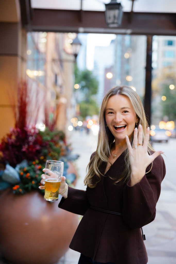 Newly engaged woman holding up her hand to show engagement ring outside Chicago bar.