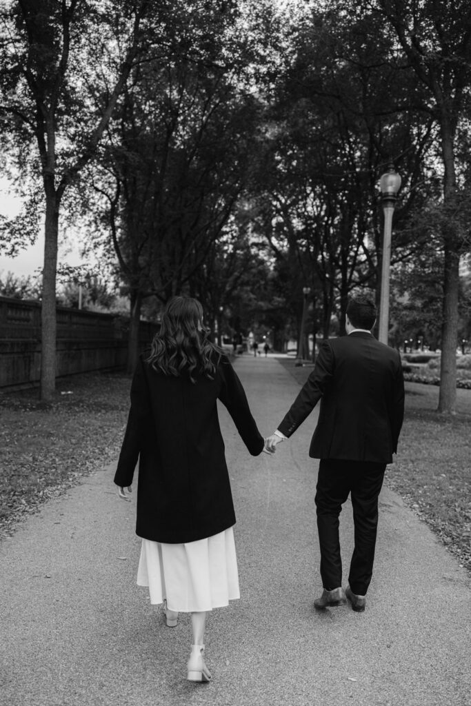 Black and white photo of couple walking together along shaded park path