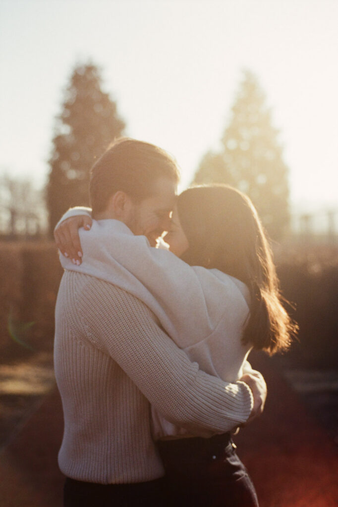 Couple embracing in soft golden sunrise light at Elawa Farm engagement session captured on film.