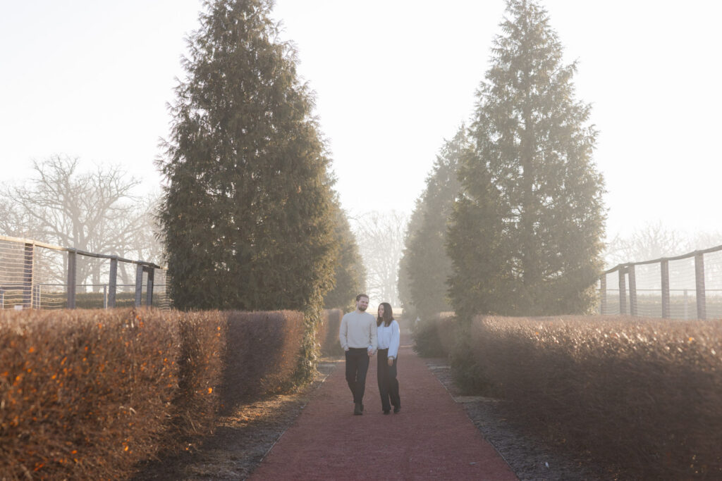 Couple walking down tree lined path at Elawa Farm during sunrise engagement session