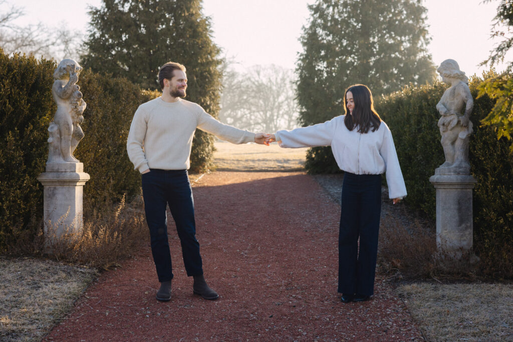 Couple holding hands and walking playfully at Elawa Farm engagement session