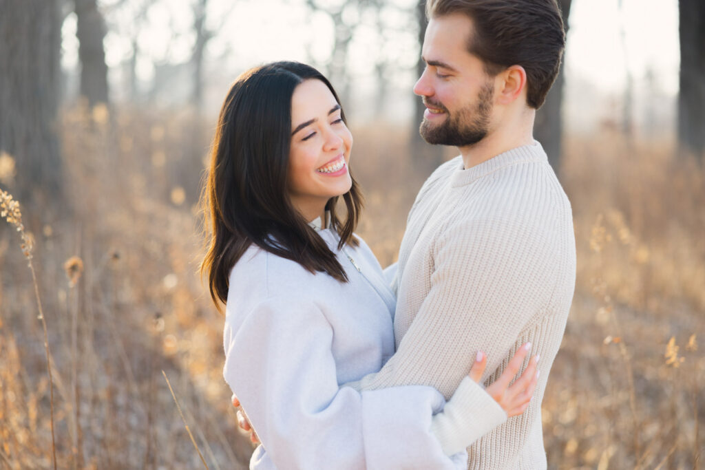 Couple standing together in tall grass during sunrise at Elawa Farm