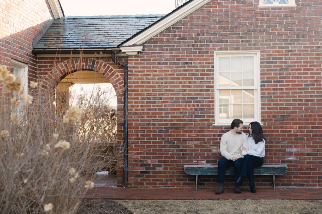 Couple sitting together on bench outside brick building at Elawa Farm