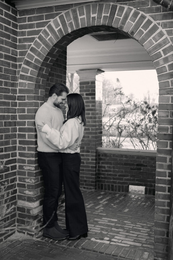 Black and white photo of couple standing under brick archway at Elawa Farm