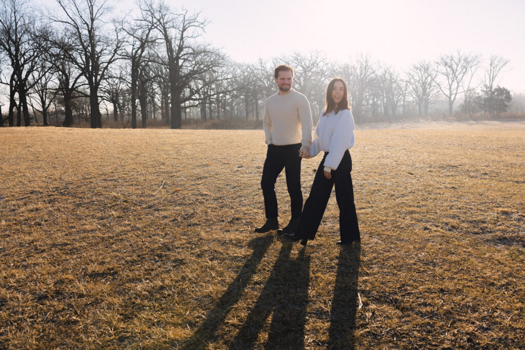 Couple walking through open field with long shadows at sunrise Elawa Farm